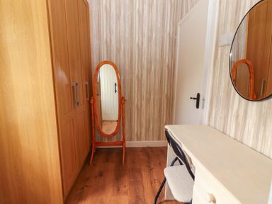 A bedroom with a wardrobe, mirror, chair, and table at The Farmhouse in Tralee, County Kerry
