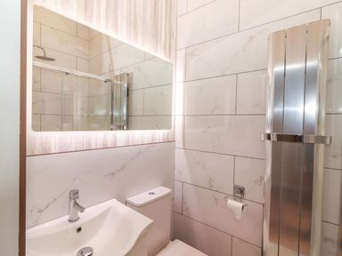 A bathroom with a sink, toilet, shower and mirror at The Farmhouse in Tralee, County Kerry