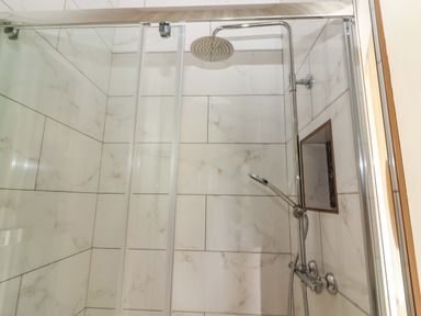 A shower with tiles and fixtures at The Farmhouse in Tralee, County Kerry