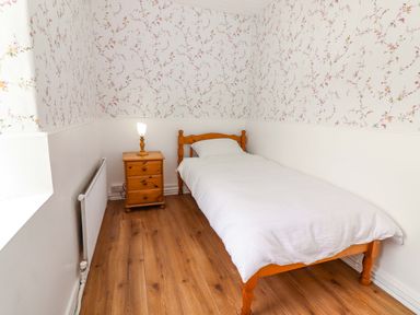 A bedroom with a single bed and nightstand at The Farmhouse in Tralee, County Kerry