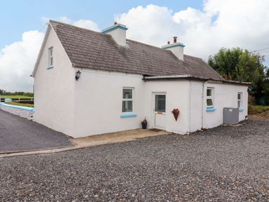 A cottage with a door and windows on a gravel driveway at The Farmhouse in Tralee, County Kerry