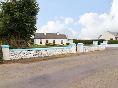A house with a stone fence and hedge at The Farmhouse in Tralee, County Kerry