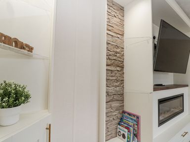 A living room with a television and books on a shelf at The Cabin in Thornton Dale