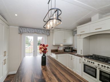 A kitchen with a gas stove and microwave at The Cabin in Thornton Dale