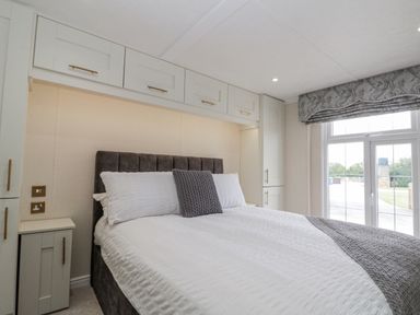 A bedroom with a bed and cabinets at The Cabin in Thornton Dale
