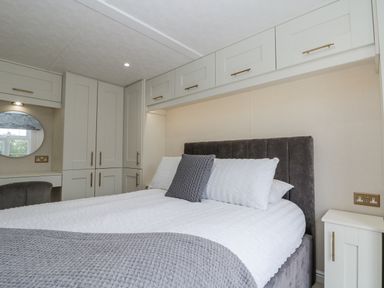 A bedroom with a bed and storage cabinets at The Cabin in Thornton Dale