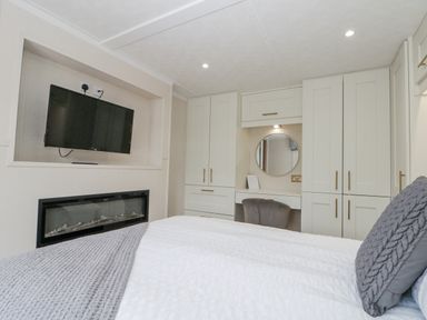 A bedroom with a bed, television, and wardrobe at The Cabin in Thornton Dale