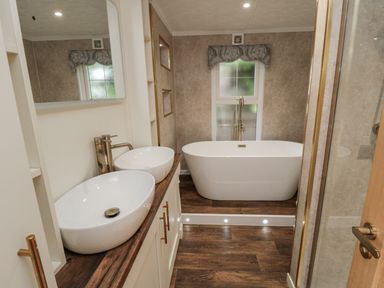 A bathroom with a bathtub and two sinks at The Cabin in Thornton Dale