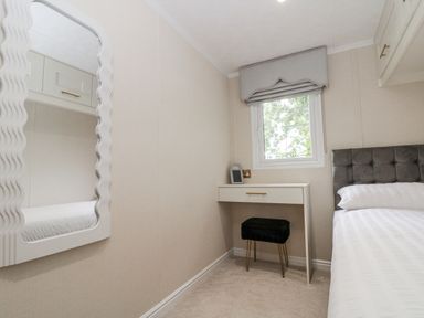 A bedroom with a bed, desk, and mirror at The Cabin in Thornton Dale
