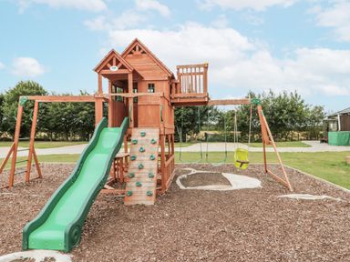 A playground with a slide and swings at The Cabin in Thornton Dale