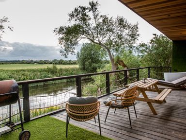 An outdoor space with seating and a table overlooking a river at The Red House in Farndon