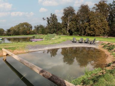 A pond with chairs and a wooden dock at The Red House in Farndon