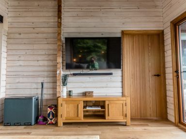 A living room with a television and media cabinet at The Larch House in Farndon