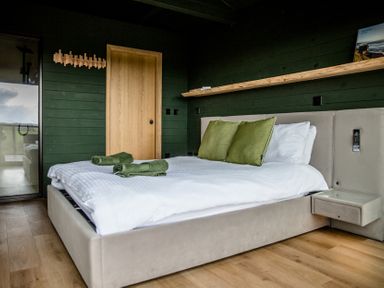 A bedroom with a bed and green pillows at The Larch House in Farndon
