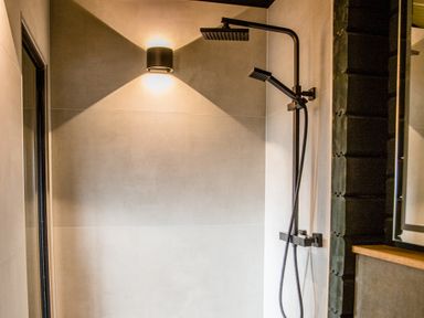 A shower with a black faucet and shower head at The Larch House in Farndon