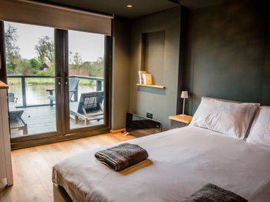 A bedroom with a bed and sliding doors leading to a deck at The Larch House in Farndon