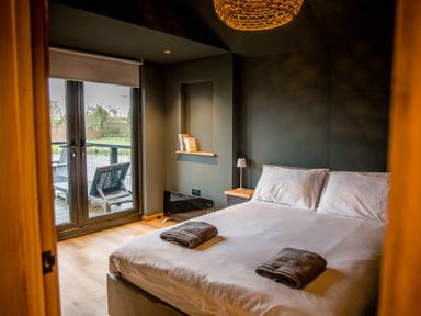 A bedroom with a bed and a balcony view at The Larch House in Farndon