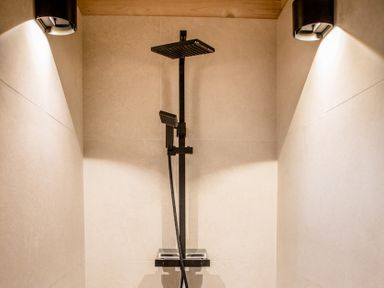 A shower setup with a black showerhead and control in a bathroom at The Larch House Farndon