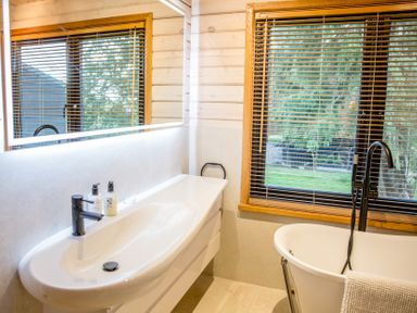 A bathroom with a bath tub, sink, and window at The Larch House in Farndon