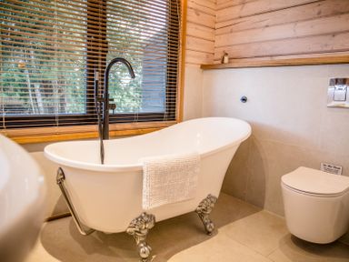 A bathroom with a bathtub and toilet at The Larch House in Farndon
