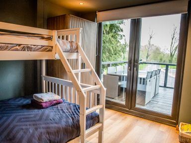 A bedroom with a bunk bed and access to a deck at The Larch House in Farndon