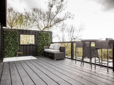 An outdoor area with a couch, bar table and stools at The Larch House in Farndon