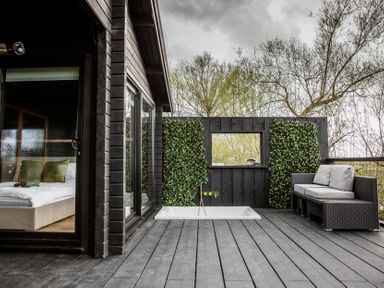 An outdoor patio with a bathtub and seating at The Larch House in Farndon