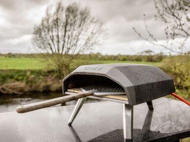 A pizza oven with a wooden peel on a table in an outdoor area at The Larch House in Farndon