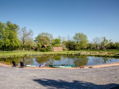 A pond with kayaks on the shore at The Larch House in Farndon
