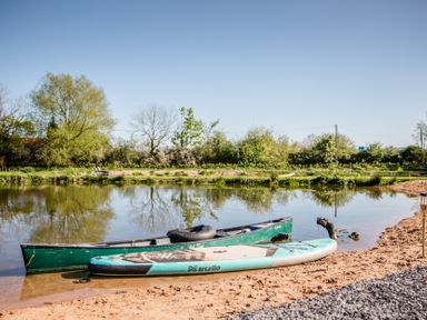 A canoe and stand-up paddleboard by the water at The Larch House in Farndon