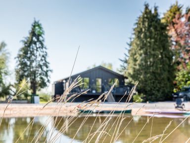 A house near water with trees and kayaks at The Larch House in Farndon