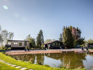 A house by a lake with trees and deck chairs at The Larch House Farndon