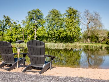 Adirondack chairs by the water in the garden at The Larch House in Farndon