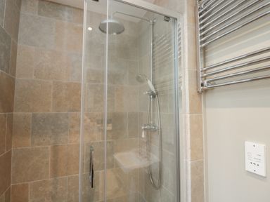 A shower with glass door and tiled walls at Granary Cottage in 