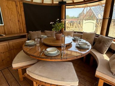 A dining room with a round table and seating at Granary Cottage in Lacock