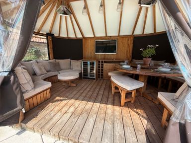 An outdoor pavilion with sofa, table, and TV at Granary Cottage in Lacock