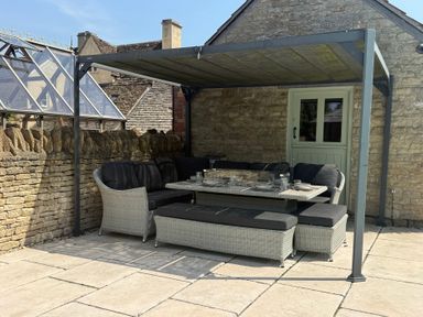 An outdoor seating area with a table and cushions at Granary Cottage in Lacock