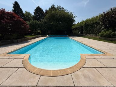 A swimming pool surrounded by a patio and garden at Granary Cottage in Lacock