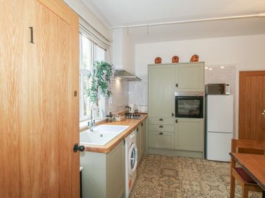 A kitchen with sink, washing machine, and cabinets at Apartment 1 The Bridge at Stanford Hotel near Great Witley