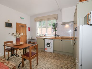 A kitchen with a washing machine and table at Apartment 1 The Bridge at Stanford Hotel near Great Witley