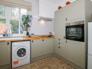 A kitchen featuring a washing machine, sink, oven, and kitchen cabinets at Apartment 1 The Bridge at Stanford Hotel near Great Witley