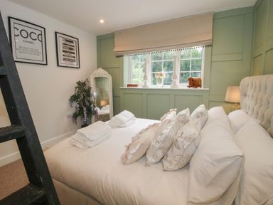 A bedroom with a bed, pillows, a lamp, and a mirror at Apartment 1 The Bridge at Stanford Hotel near Great Witley