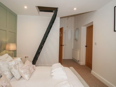 A bedroom with bedding and a ladder at Apartment 1 The Bridge at Stanford Hotel near Great Witley