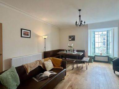 A dining room with a table and sofa at Llanrwst Apartment