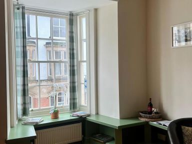 A sitting area with a window and green table at Llanrwst Apartment