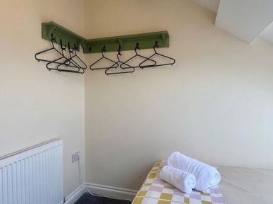 A bedroom with hangers on a shelf and towels on a bed at Llanrwst Apartment