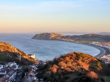 A view of a coastline with hills and buildings at Mariners Lee in Llandudno