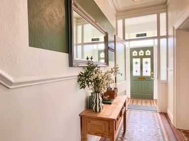 A hallway with a console table and a green door at Clarence House in Llandudno