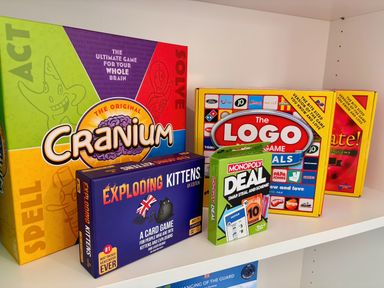 A shelf with board games including Cranium and Exploding Kittens at Clarence House in Llandudno