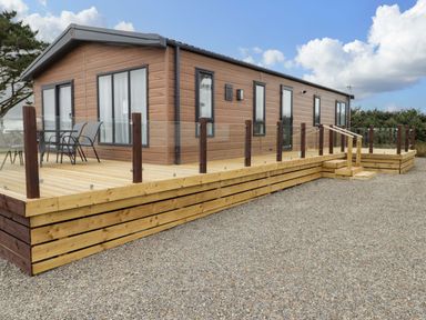 A cabin with a wooden deck and chairs at Dolphin in Haverfordwest